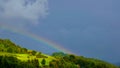 The bright sun creates a rainbow over the hill, a few moments after heavy rain Royalty Free Stock Photo