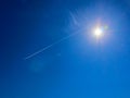 Bright sun with flares and spectral aureole around against blue sky