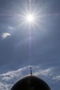 The bright sun is high in the sky above the golden minaret of the Moslem mosque. Silhouette of the symbol of the Islamic religion