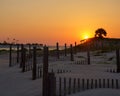 Bright sun in orange sunset sky shining over wooden fences on sandy Saint George Island, Florida