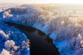 Bright sun rises over winter village, aerial landscape. River flows along rural area, beautiful scenery Royalty Free Stock Photo