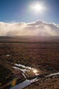 Bright sun shines over low clouds above vast and empty land along Volcanic Loop Hwy and Desert Road. Central Plateau