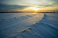 Bright sun sunset winter with road and footprints in the snow. Royalty Free Stock Photo