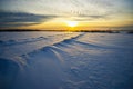 Bright sun sunset winter with road and footprints in the snow. Royalty Free Stock Photo