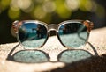Stylish sunglasses with reflective lenses resting on a textured surface outdoors Royalty Free Stock Photo