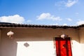 Bright sunlight shining on an old yunnanese house, beautiful colors of red door, blue sky and shadow on wall. Doi Mae Salong,