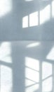 Bright sunlight streams through a window, casting intricate shadows on a textured minimalist room Royalty Free Stock Photo