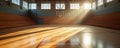 Bright sunlight streams through windows in empty basketball court. Hardwood floor reflects light and shadows creating visual Royalty Free Stock Photo