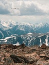 Bright sunny atmospheric scenery on top of spotted snow mountain ridge under dark clouds. Beautiful vertical landscape with