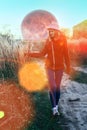 A bright sunny day, a girl in a red jacket and gray hat walking along the field along the rural road. In the background is a huge Royalty Free Stock Photo