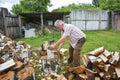 On a sunny summer day, a man is chopping firewood in the yard