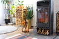 Bright sunny interior of the house with Black Metal Steel fireplace stove with fire and firewood with halloween decor and autumn