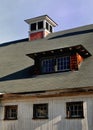 Bright sunny late fall day highlights the cupola and windows on a dirty New England white barn