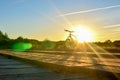 Bright sunrise on the road near the river on the background of a bicycle. Mountain bike in forest with sun rays Royalty Free Stock Photo