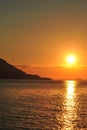 Bright sunset with large yellow sun under the sea surface. Beautiful Sunset in tropical Komodo island, Labuan Bajo, Fores,