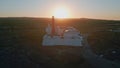 Bright sunset light shining at high seaside lighthouse aerial view. Red beacon Royalty Free Stock Photo