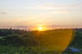 Bright sunset over a green meadow and forest in summer Royalty Free Stock Photo