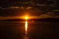 Bright sunset in the river, orange sky in dark clouds and reflection of the sun in the water Royalty Free Stock Photo