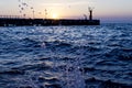 Bright sunset under the sea and pier with waves splashes. Royalty Free Stock Photo