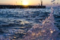 Bright sunset under the sea and pier with waves splashes. Royalty Free Stock Photo