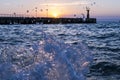 Bright sunset under the sea and pier with waves splashes. Royalty Free Stock Photo