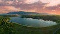 Sunset sun illuminates fields, silhouettes of Balkan mountains and lake. Panorama, top view Royalty Free Stock Photo