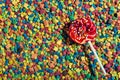 A bright sweet Lollipop on a stick lies on colorful pastry sprinkles