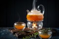 Bright tea with sea buckthorn orange in a glass teapot wooden Board on a dark background