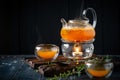 Bright tea with sea buckthorn orange in a glass teapot wooden Board on a dark background