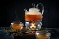 Bright tea with sea buckthorn orange in a glass teapot wooden Board on a dark background