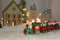 Bright toy train near decorative houses with Christmas lights on artificial snow Royalty Free Stock Photo