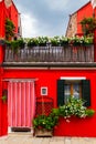 Bright traditional red house on Burano island, Venice, Italy. Colorful curtain on door, wooden old style window with Royalty Free Stock Photo