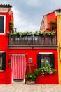 Bright traditional red house on Burano island, Venice, Italy. Colorful curtain on door, wooden old style windows with Royalty Free Stock Photo