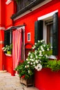 Bright traditional red house on Burano island, Venice, Italy. Colorful curtain on door, wooden old style windows with Royalty Free Stock Photo