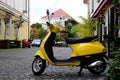 Bright trendy yellow Italian made scooter in old street with cobblestone