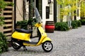 Bright trendy yellow Italian made scooter in old street with cobblestone