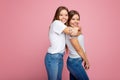 Bright two young twin sisters with beautiful smile walk over pink background. Royalty Free Stock Photo