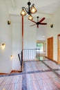 Bright upstairs hallway with tile floor, high ceiling and staircase.