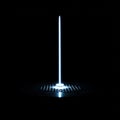A bright, vertical beam of light emerges from a perforated circular platform against a Royalty Free Stock Photo