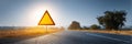 Bright Warning Sign Stands Tall Beside an Empty Road at Sunset, Casting Warm Light Over the Landscape Royalty Free Stock Photo