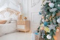 Bright White Bedroom Interior with Christmas New Year Tree decor and lights bokeh on the background Royalty Free Stock Photo