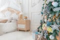 Bright White Bedroom Interior with Christmas New Year Tree decor and lights bokeh Royalty Free Stock Photo