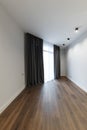 Bright white empty room, stylish interior design of the apartment. Designer gray curtains, brown parquet and white walls.