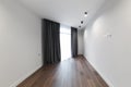 Bright white empty room, stylish interior design of the apartment. Designer gray curtains, brown parquet and white walls.