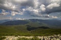 Bright white puffy clouds lit by sun spreading against blue summer sky over green mountain ridge Royalty Free Stock Photo