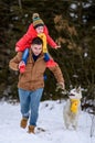 Bright winter day dad with daughter in the woods with their dog, fun walk in the snowy forest. Royalty Free Stock Photo