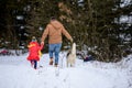 Bright winter day dad with daughter in the woods with their dog, fun walk in the snowy forest. Royalty Free Stock Photo