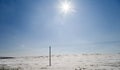 The bright winter sun shines over a frozen field on a hill with a power line Royalty Free Stock Photo