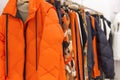 Bright women`s clothes on hangers in the store. Jackets, jumpers and blouses. Close-up