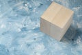 Bright wood cube on white and blue painting surface. Wooden cube and a piece of fine art studio shot. Royalty Free Stock Photo